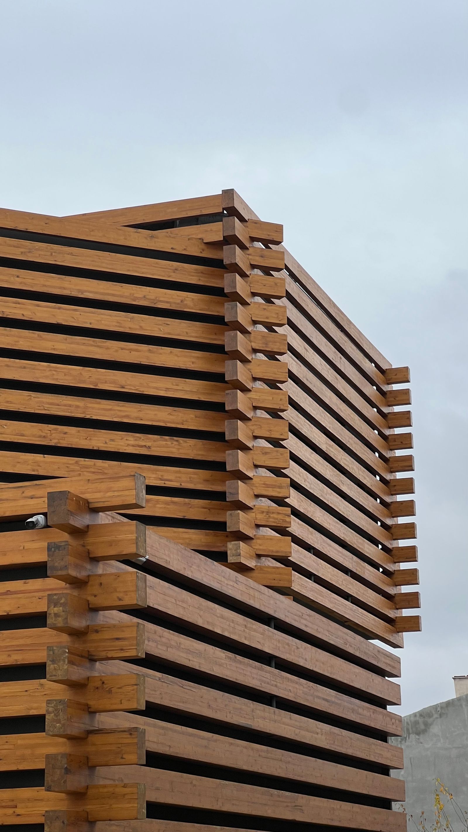 Detail einer modernen Fassade aus Holzlamellen vor blauem Himmel